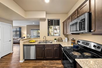 A modern kitchen with dark wood cabinets and stainless steel appliances. at The Fairways by Picerne Apartments, Las Vegas, NV